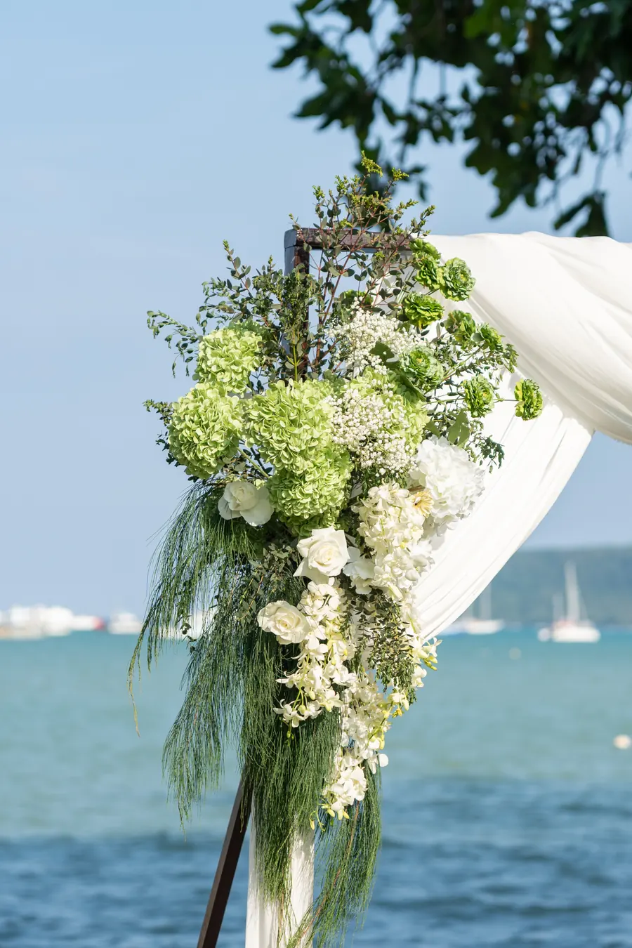 White flowers and flowing fabric on the wedding arch overlooking Chalong Bay