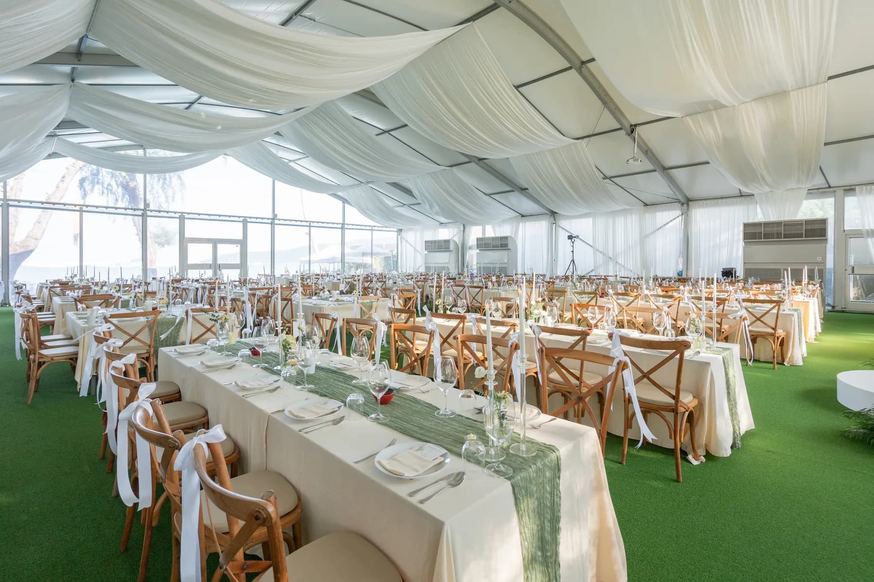 Long wedding banquet tables, white flowers and wooden chairs beneath flowing fabric at KEP